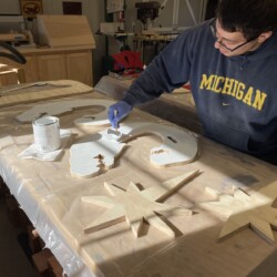 Applying white paint to the components that will be attached to the "O" letters with stainless steel wood screws