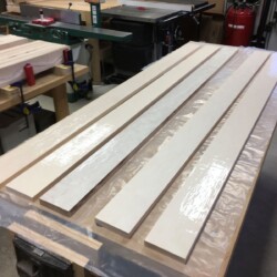 Working quickly, a grooved rubber roller spreads out glue in an even layer