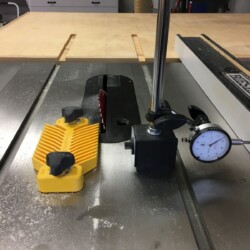 Using a dial indicator to make 0.010" adjustments to the rip fence for cutting a twenty-one degree bevel on the upper carcass top panel to match the sides