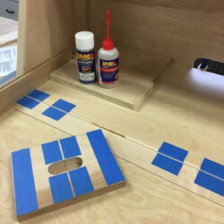 A technique from the CNC router, painter's tape on jig and components with a few drops of CA glue hold the jig firmly in place for routing the hinge mortises